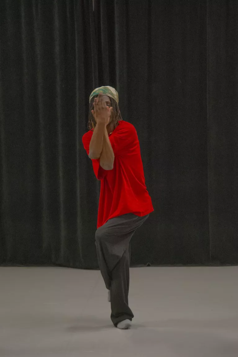 Un jeune qui danse au centre de l'image avec les mains croisées devant le visage