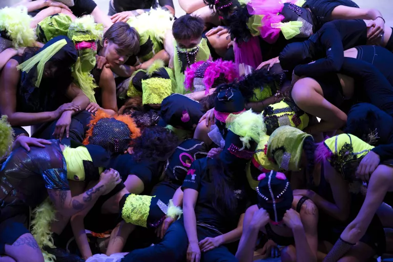 Un groupe de personnes avec des cagoules colorées s'accrochent les unes aux autres avec leurs bras