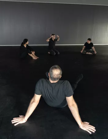 Quatre personnes assises au sol dans une salle sombre.