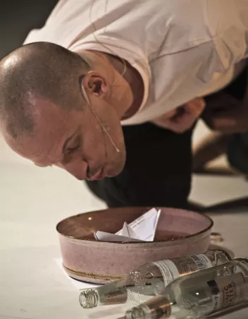 A person is leaning over a container holding a paper boat.