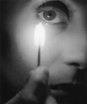 Black-and-white photograph of a face with a lit candle