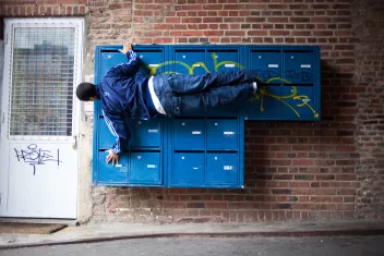 photo of a dancer standing upright next to a blue postbox