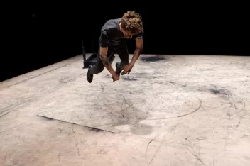 Photo of a performance showing a dancer leaping towards the floor