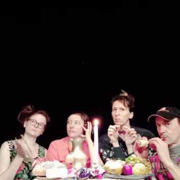 Four dancers are sitting at a table, each looking in a different direction