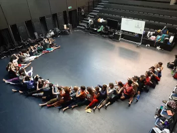 Dance workshop with dancers seated one behind the other in a semicircle