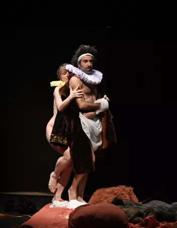 photo d'un spectacle avec 2 danseurs l'un derrière l'autre, des costumes baroques sur eux et au sol