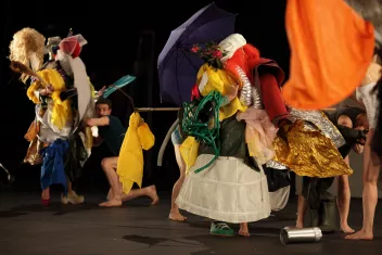 Des danseurs sont recouverts d'une multitude d'habits et de tissus colorés