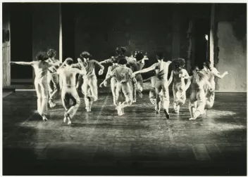 Black-and-white photograph of an Andy Degroat performance featuring dancers moving towards the back of the stage