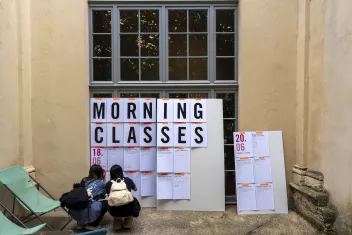 Photo of two Camping participants crouching in front of the event schedule