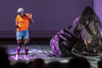 Photo du spectacle "Filles Petroles" avec un sol et une structure recouverts d'un plastique noire et une danseuse.