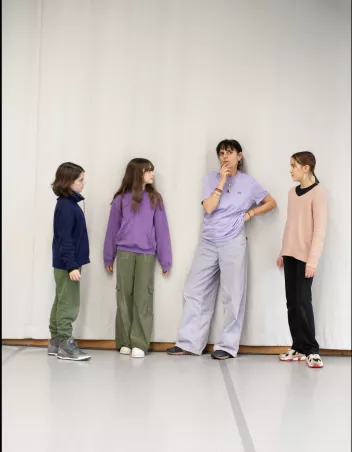 Photo of an adult who appears to be deep in thought, surrounded by three teenage girls standing nearby 