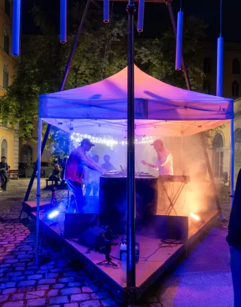 photo of a DJ under a marquee at a party