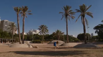 a photo of a dancer with long hair, her head bowed, on a plot of land with palm trees