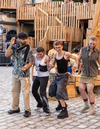 A photo of four people in the SUBS courtyard in Lyon, holding hands and moving their legs in unison