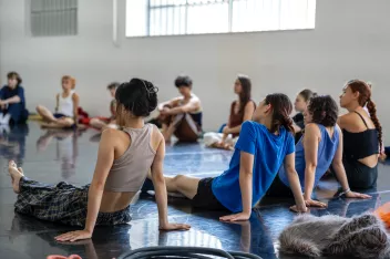 photo of dancers sitting in a circle in a studio 