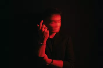 photo d'une personne sur fond noir éclairée par une lumière rouge