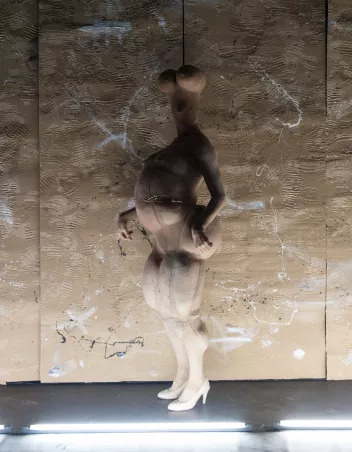a photo from the show ‘Relic’ by Euripides Laskaridis, featuring the choreographer on stage, dressed in a beige jumpsuit