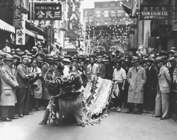 Black-and-white photo taken in Chinatown, New York, showing a dragon dance performance
