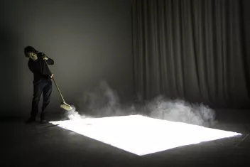 photo d'un spectacle avec au sol un tapis éclairé recouvert de poussière et une personne qui le balaye