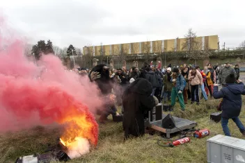 Photo de la performance "Emmitouflé" de Boris Charmatz en extérieur avec de la fumée rouge et le public qui assiste à la performance
