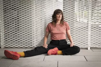 Portrait photo de Faye Driscoll assise devant une grille