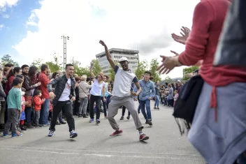 Danseurs qui défilent en extérieur en dansant entourés du public