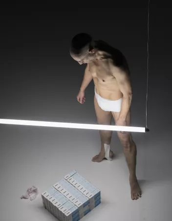 photo d'un danseur en slip devant un néon allumé