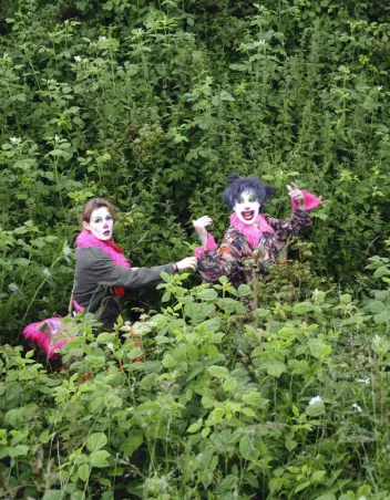 Photo de Isa Frémeaux et Jay Jordan au milieu de feuillages maquillés en clown