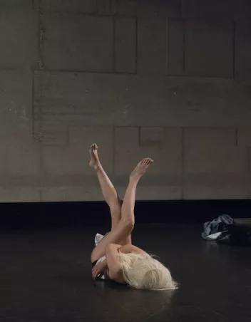 photo d'un spectacle avec une danseuse allongée sur le sol, recouverte d'une perruque blonde, les jambes levées