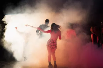 Photo of people dancing with their backs to the camera at a party with smoke