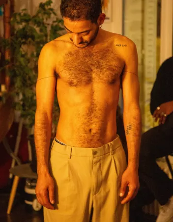Photo of Mohamed Issaoui in character, bare-chested and wearing beige trousers