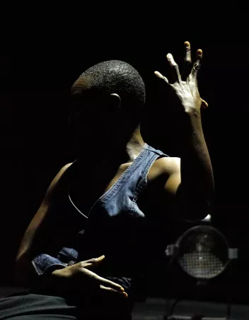 A photo of Bintou Dembélé, seen in profile with her left arm raised