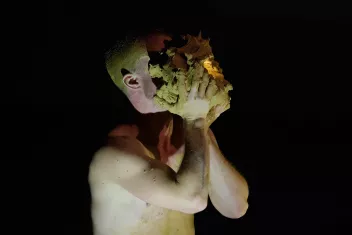 Photo du spectacle "La grotte" de Pol Pi, un danseur masque son visage avec de l'argile vert