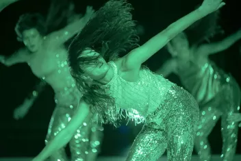 a photo of a show featuring green lighting and dancers wearing sequinned outfits
