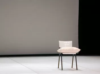 photo d'une scène de spectacle avec une chaise blanche et un coussin posé dessus