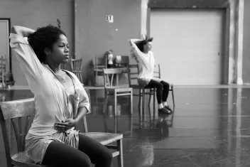 photo en noir et blanc du spectacle "Rosas danst Rosas" avec deux danseuses assises sur des chaies