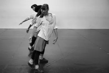 Photo en noir et blanc de trois danseurs alignés, en mouvement
