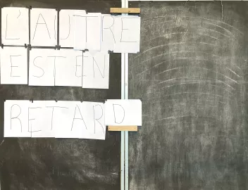 Photo d'un tableau noir d'école avec des lettres sur feuilles blanches qui écrivent "l'autre est en retard"