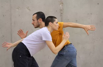 Two dancers pass each other whilst frozen in a running position