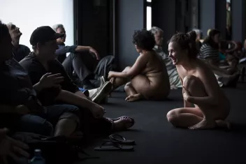 photo d'une représentation avec des femmes nues qui s'adressent au public, assis.