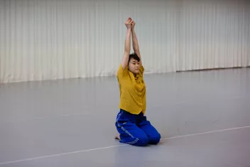 photo d'une danseuse à genoux, les bras levés, les mains jointes
