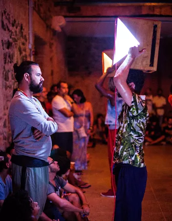 Danseurs qui portent des projecteurs face à des spectateurs debouts