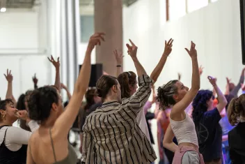 photo d'un atelier de danse avec des danseurs de dos, le bras droit levé