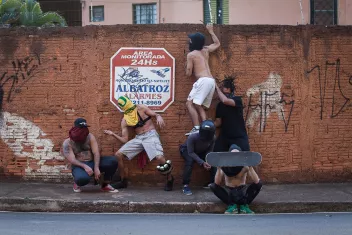 Danseurs avec les visages masqués devant un mur de briques