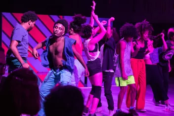 photo du spectacle "Quando Quebra Queima" avec danseurs éclairés par une lumière rose
